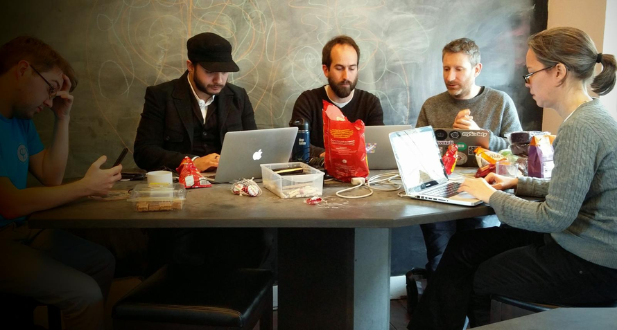 Mark sat at a table, typing into a laptop with other volunteers, surrounded by snacks