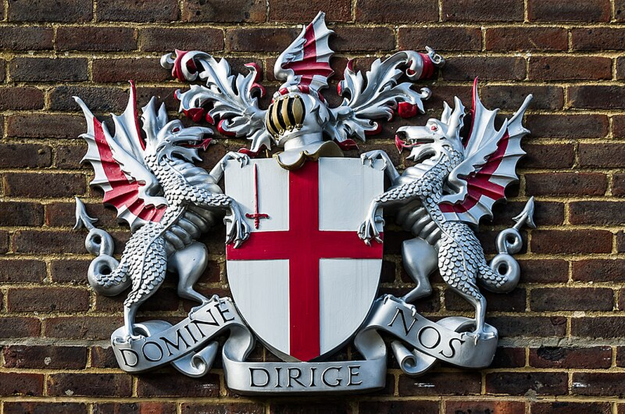 The coat of arms of the City of London, set on a brick wall