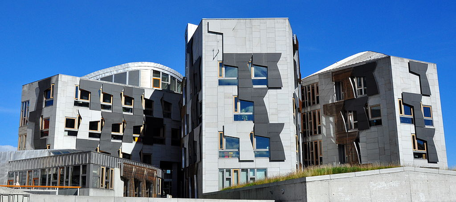 Three grey office blocks against a blue sky, part of the Scottish Parliament at Holyrood.