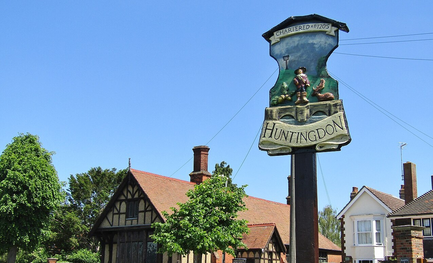 The town sign of Huntingdon, against a clear blue sky and a redbrick building. Lovely.
